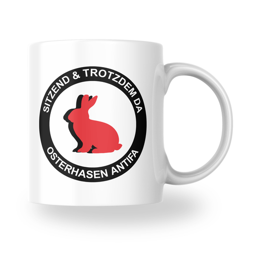 „Sitzend & trotzdem da – Osterhasen Antifa“ – Keramiktasse (325 ml)